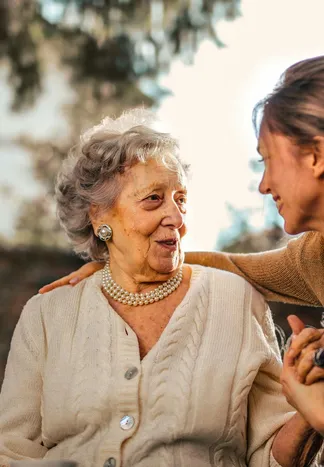 Younger woman sharing a warm conversation with elderly woman outdoors